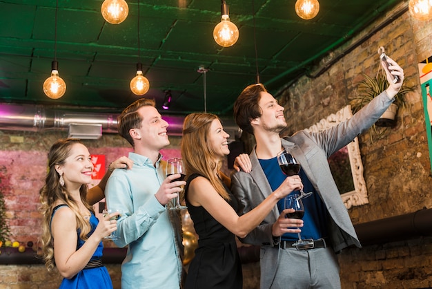 Groupe D'amis Prenant Selfie Sur Téléphone Portable En Soirée