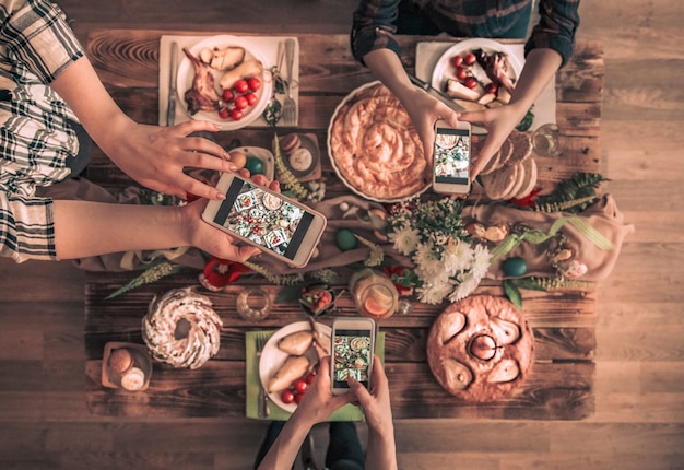 Un groupe d'amis prend une photo avec un téléphone portable avant de déjeuner. vue de dessus.