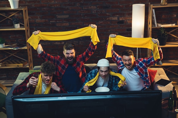 Photo gratuite groupe d'amis regardant la télévision, match de sport ensemble. des fans émouvants acclamant l'équipe préférée, regardant un football passionnant. concept d'amitié, d'activité de loisirs, d'émotions.