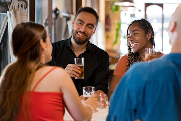 Groupe d'amis s'amusant ensemble tout en buvant un verre de bière dans un bar. Notion d'amis.