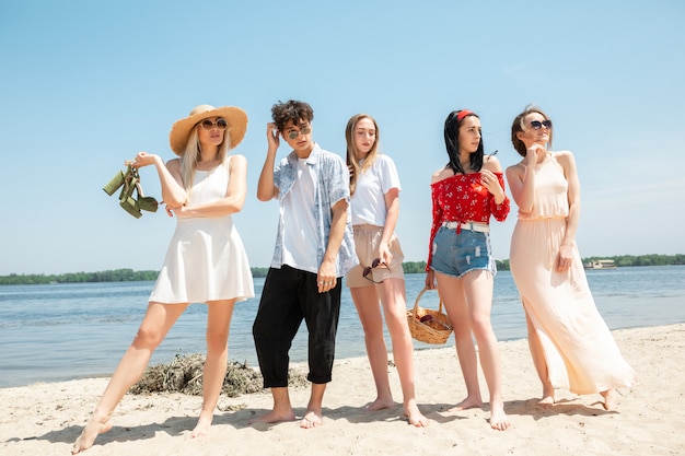 Groupe d'amis s'amusant sur la plage en journée d'été ensoleillée