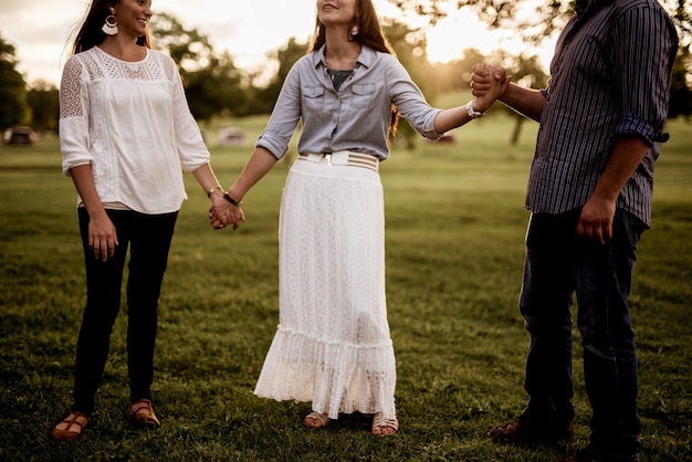 Groupe d'amis se tenant la main dans le parc et priant