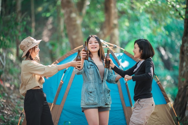 Groupe de belles femmes asiatiques amis voyageurs se détendant devant la tente de camping Ils aiment parler et boire de la bière avec plaisir et heureux ensemble