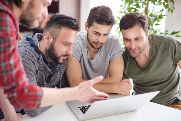 Groupe ciblé d'hommes assis devant l'ordinateur portable