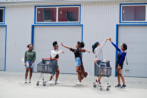 Groupe de cinq femmes afro-américaines avec des caddies s'amusant ensemble en plein air