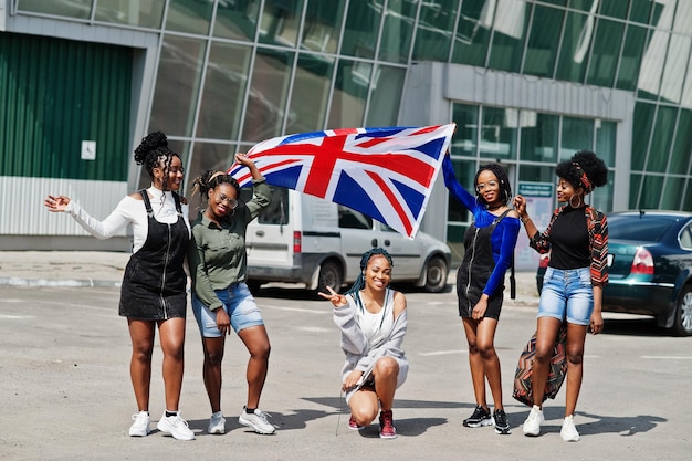 Photo gratuite groupe de cinq femmes afro-américaines marchant ensemble sur le parking avec le drapeau de la grande-bretagne