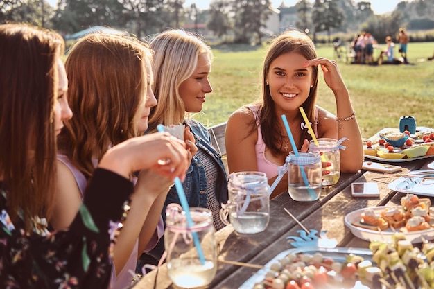 Groupe de copines assises à la table ensemble pour célébrer un anniversaire au parc extérieur.