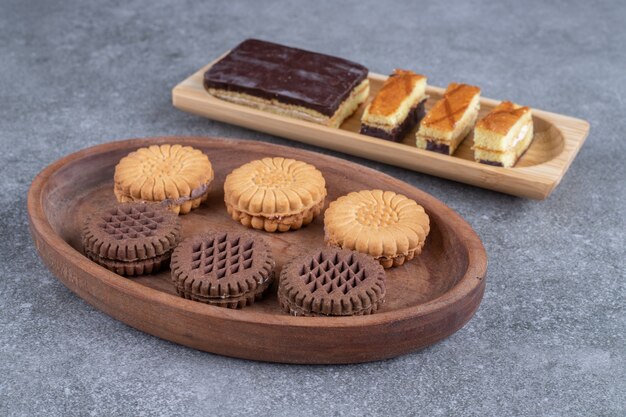 Groupe de délicieux biscuits et tranches de gâteau sur des assiettes en bois