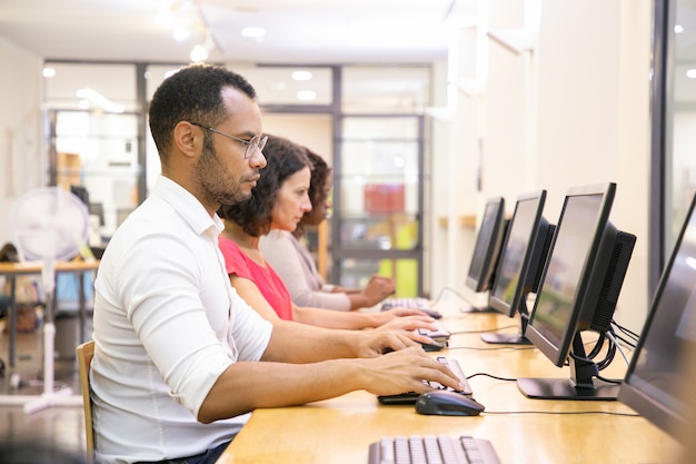 Groupe diversifié d'étudiants prenant des tests en ligne