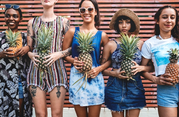 Un groupe diversifié de femmes debout et tenant des ananas ensemble