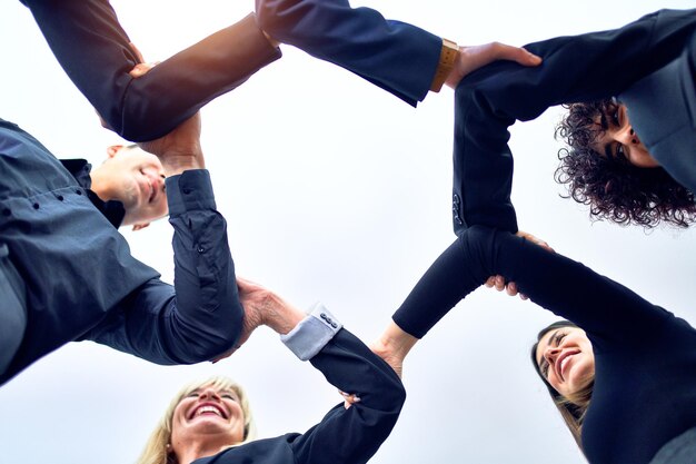 Groupe d'employés d'affaires debout les mains jointes au bureau