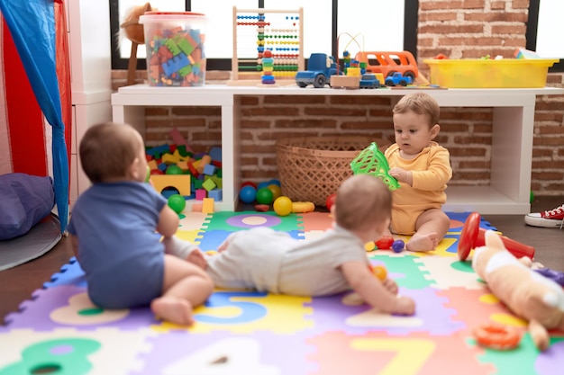 Photo gratuite groupe d'enfants en bas âge jouant avec des jouets rampant sur le sol à la maternelle