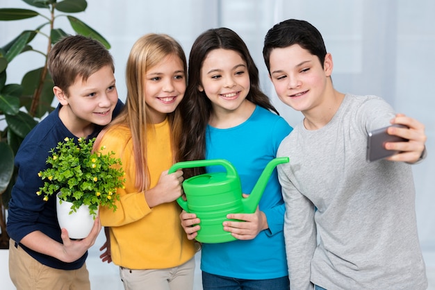 Groupe d'enfants prenant selfie tout en arrosant des fleurs