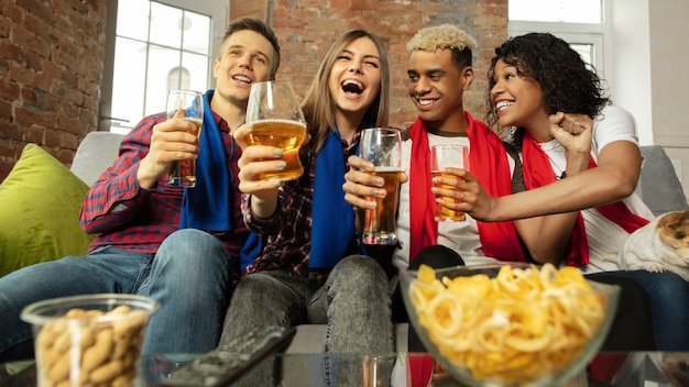 Groupe enthousiaste de personnes regardant le championnat de match de sport à la maison