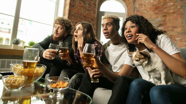 Groupe enthousiaste de personnes regardant le championnat de match de sport à la maison