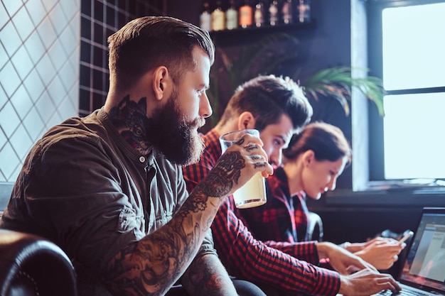 Photo gratuite groupe d'étudiants assis sur le canapé se reposant dans un café et travaillant avec un ordinateur portable sur un projet commun.