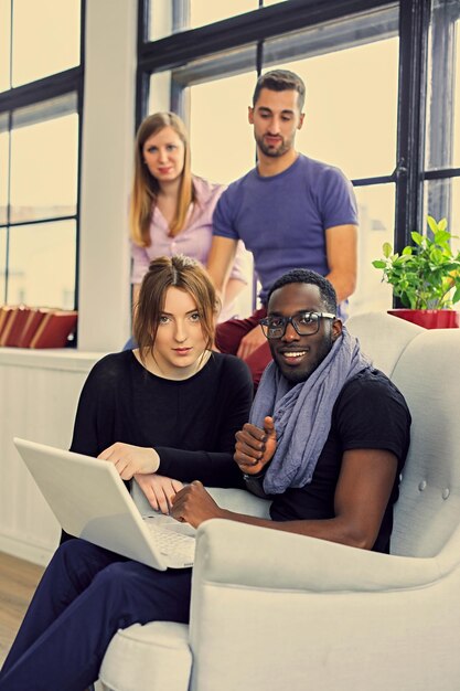 Groupe d'étudiants multiraciaux utilisant un ordinateur portable. Image aux tons chauds filtrée.