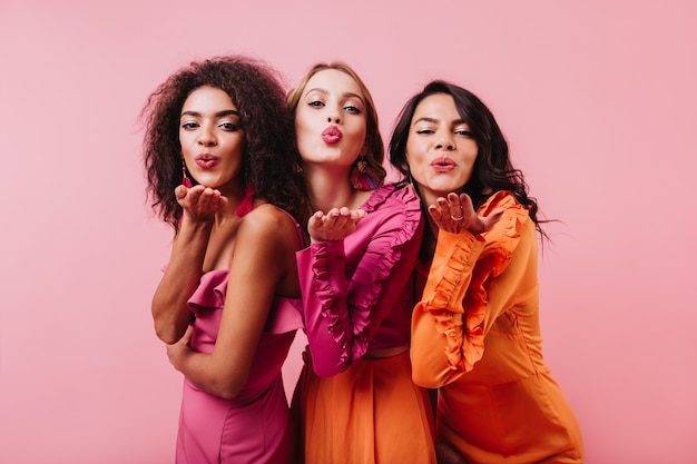 Photo gratuite groupe de femmes envoyant des baisers aériens sur mur rose