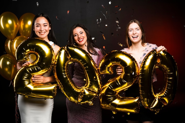 Groupe de femmes posant avec des ballons d'or à la fête du nouvel an