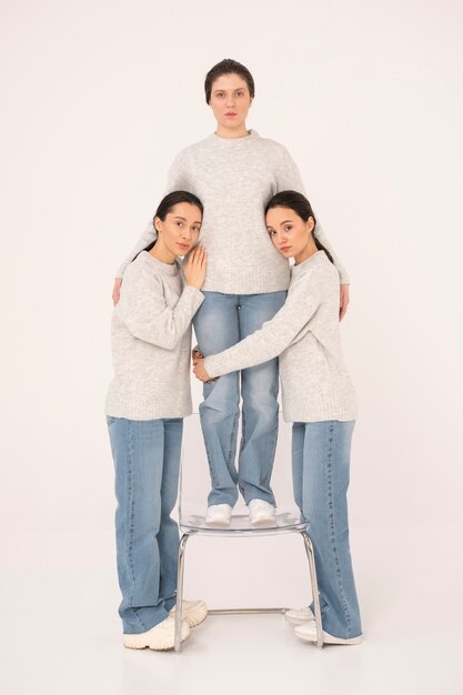 Groupe de femmes en pulls et jeans posant pour des portraits minimalistes avec chaise