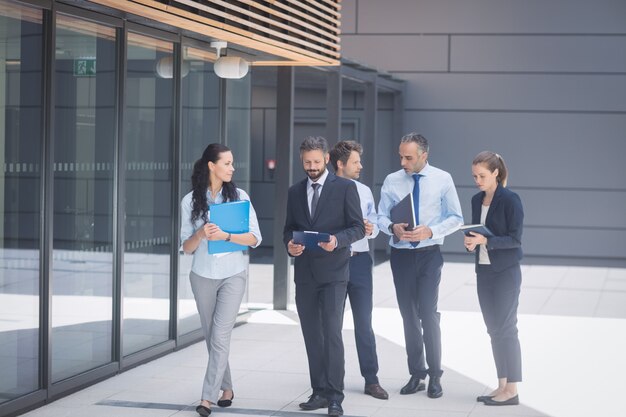 Groupe de gens d'affaires marchant à l'extérieur de l'immeuble de bureaux