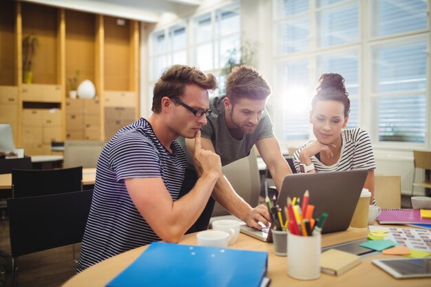 Groupe de graphistes discuter sur ordinateur portable à leur bureau