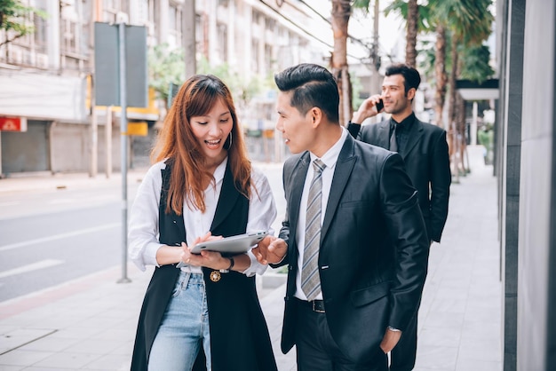 Groupe d'hommes d'affaires asiatiques dans le quartier des affaires parlant de nouvelles affaires et économiques sur un emplacement extérieur