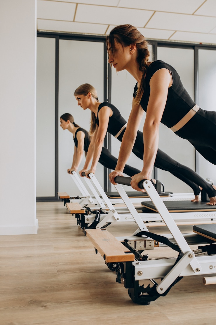 Photo gratuit groupe d'instructeurs de pilates exerçant sur les réformateurs
