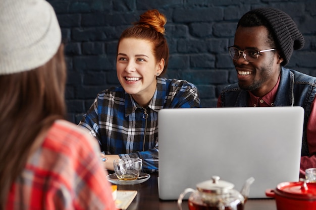 Photo gratuite groupe interracial de jeunes hipsters utilisant des gadgets modernes au café. concept de processus d'affaires, d'amitié, de démarrage, de travail d'équipe et de coworking.