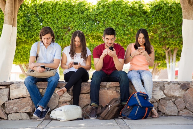 Photo gratuite groupe de jeunes adultes utilisant leur smartphone à l'école