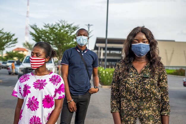 Groupe de jeunes africains avec des masques debout dans la rue