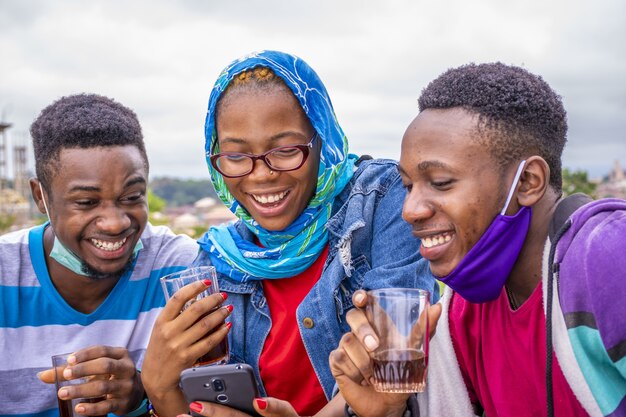 Groupe de jeunes amis buvant du vin et utilisant leur téléphone dans un parc