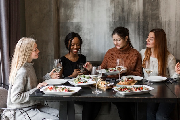 Groupe de jeunes femmes en train de dîner et de vin ensemble