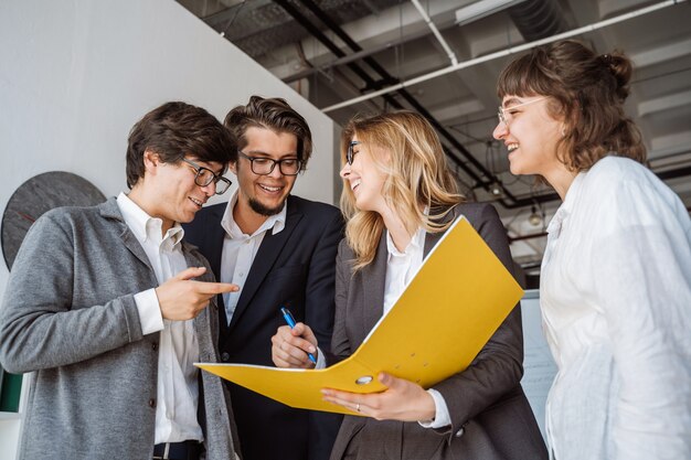 Groupe de jeunes inspirés debout et discutant d'un nouveau projet