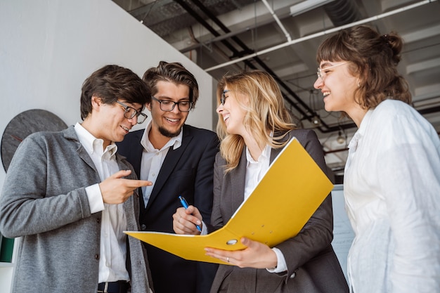 Groupe de jeunes inspirés debout et discutant d'un nouveau projet