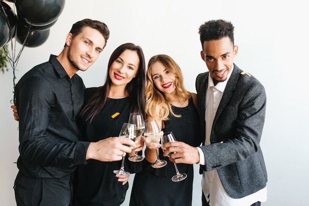 Groupe de jeunes joyeux dans des vêtements à la mode en levant des verres de champagne