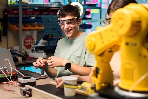 Groupe de jeunes portant des lunettes de protection faisant des expériences en robotique dans un laboratoire Robot