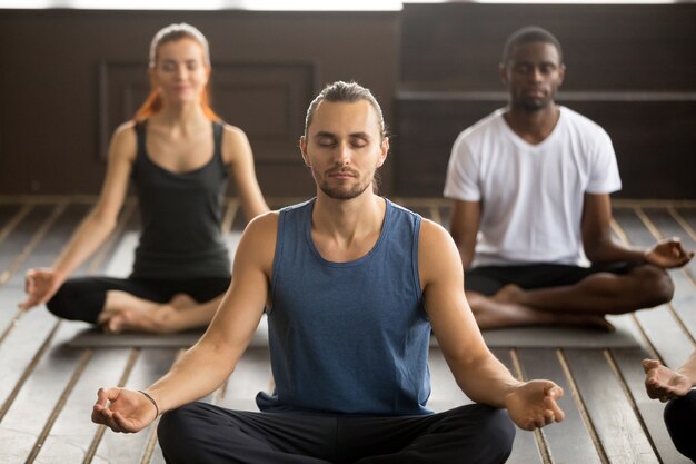 Groupe de jeunes sportifs assis à l'exercice de Sukhasana