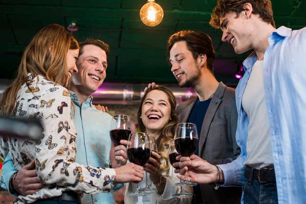 Groupe de joyeux amis profitant d&#39;un verre en soirée au bar