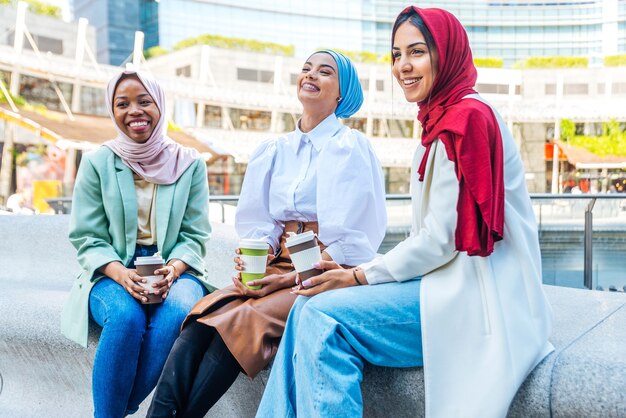 Groupe multiethnique de filles musulmanes portant des vêtements décontractés et des liens traditionnels avec le hijab et s'amusant à l'extérieur - 3 jeunes filles arabes