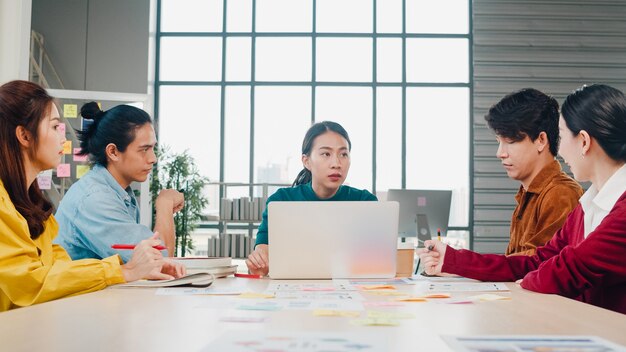 Groupe multiracial de jeunes créatifs dans des vêtements décontractés intelligents discutant des idées de réunion de brainstorming d'affaires projet de conception de logiciel d'application mobile dans un bureau moderne. Concept de travail d'équipe de collègue.