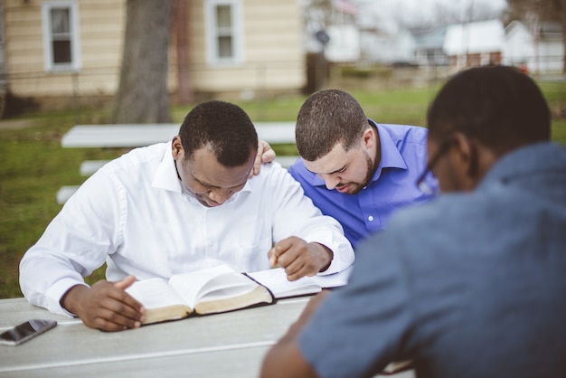 Photo gratuite groupe de personnes diverses assis à la table et lisant la bible