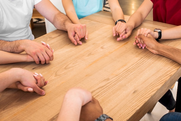 Groupe de personnes diverses, main dans la main sur un bureau en bois