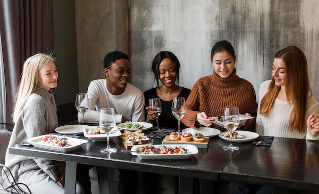 Groupe de personnes positives en train de dîner ensemble