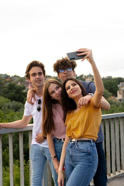 Groupe de quatre amis passant du temps ensemble à l'extérieur et prenant un selfie