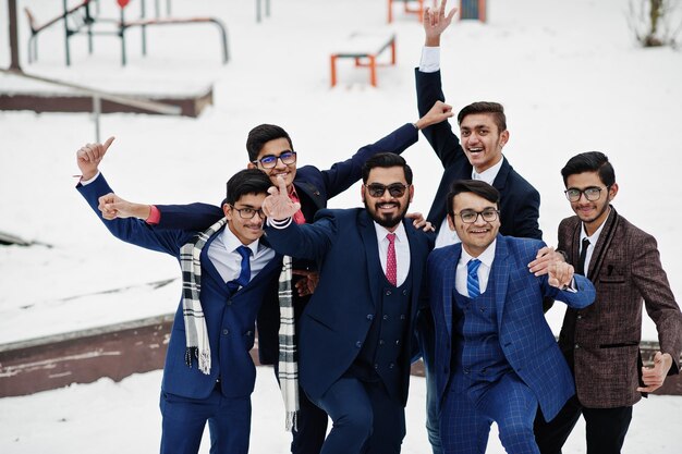 Groupe de six hommes d'affaires indiens en costumes posés à l'extérieur en hiver en Europe câlins et émotions heureuses