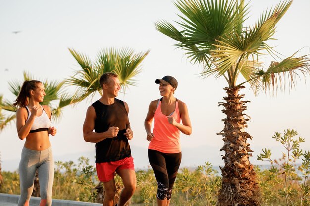 Groupe de sportifs heureux faisant du jogging et se parlant à l'extérieur.