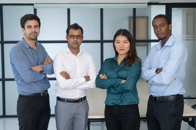 Groupe de travail multiethnique posant dans un bureau moderne.