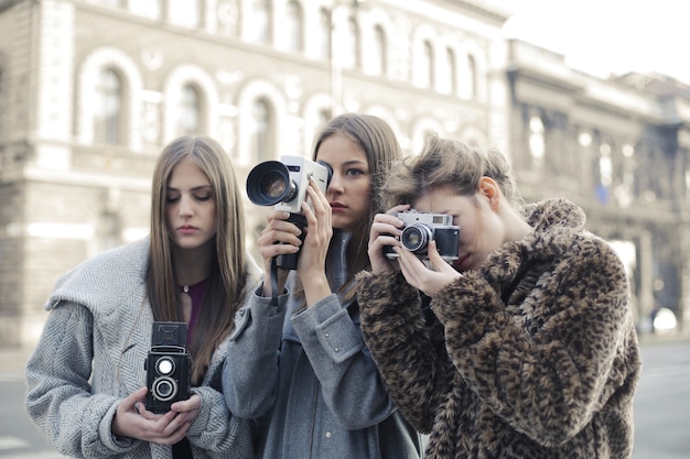 Groupe de trois amies prenant des photos avec leurs appareils photo