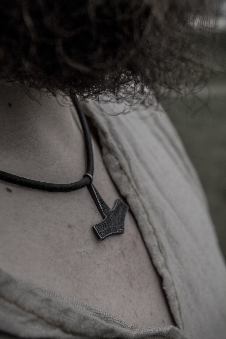 Photo gratuit guerrier viking aux cheveux bouclés portant un collier de marteau
